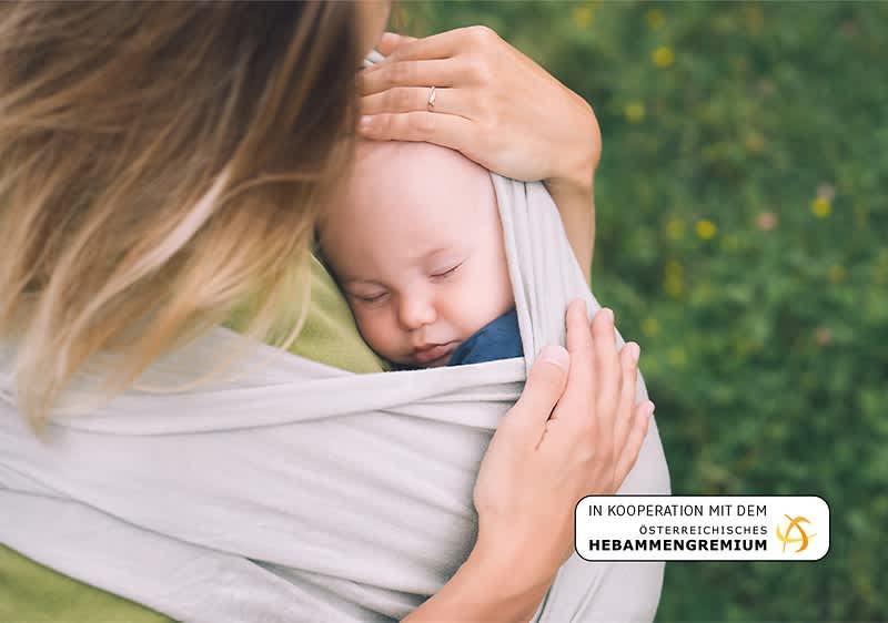 Mutter traegt Baby in Tuch