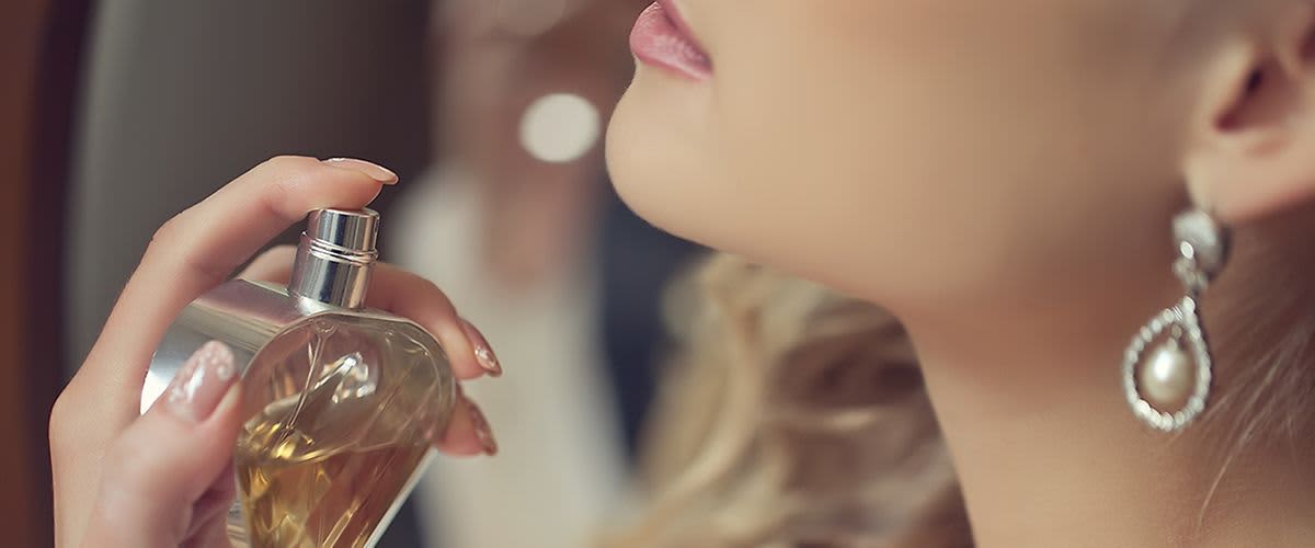 Frau sprüht Duft auf ihren Hals