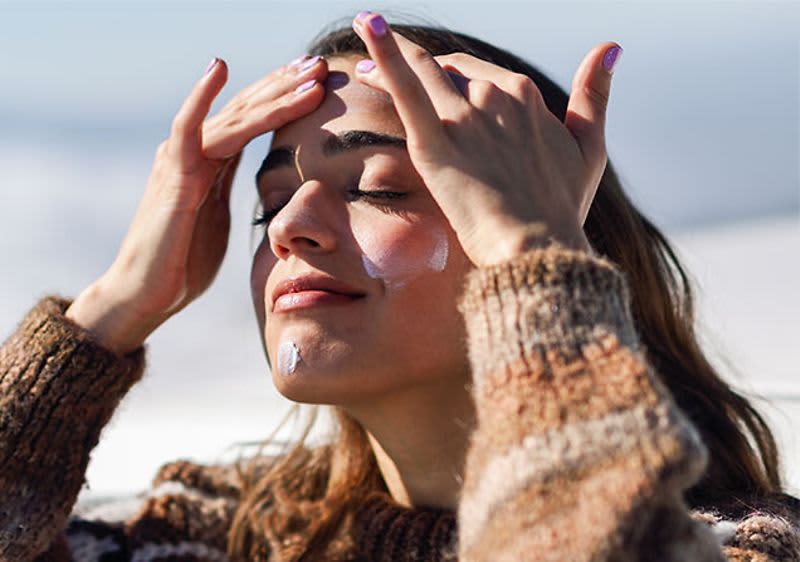 Frau, die sich mit Sonnencreme eincremt