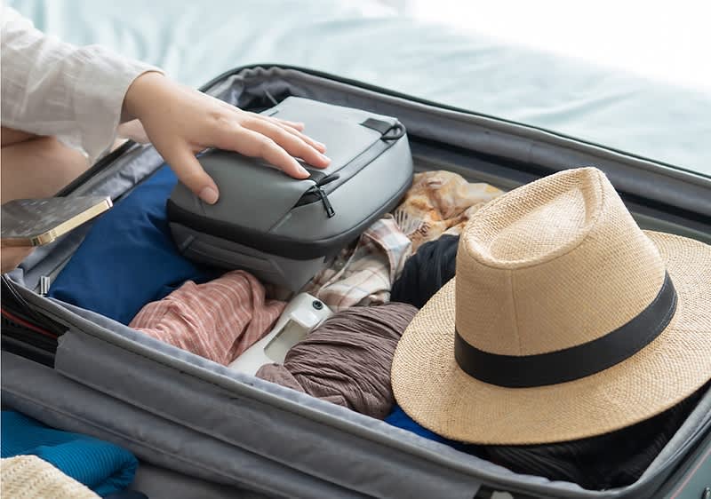 Kofferpacken mit Kleidung und Strohhut