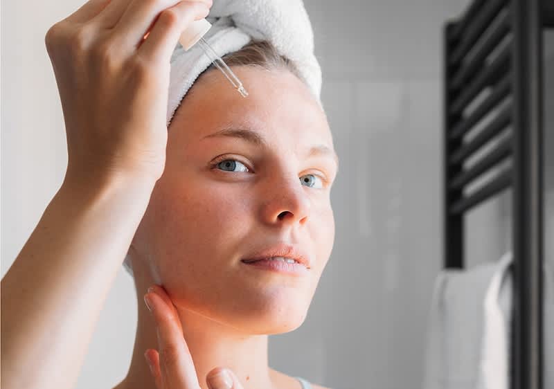 Frau tropft Rosenwasser ins Gesicht