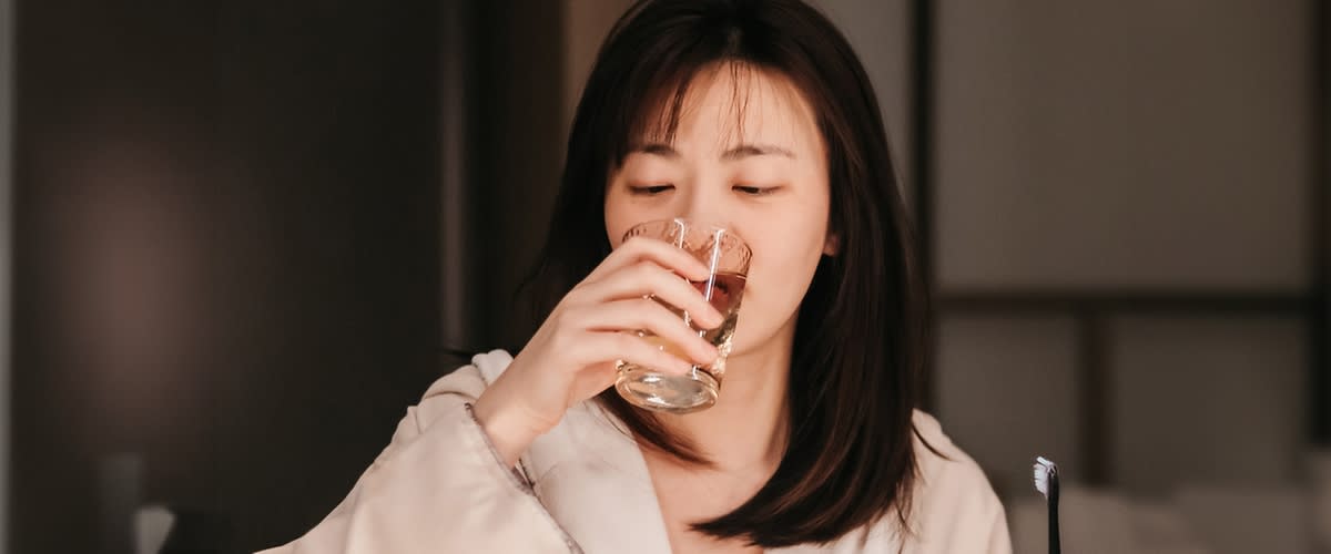 Frau mit Zahnfleischentzuendung trinkt Wasser