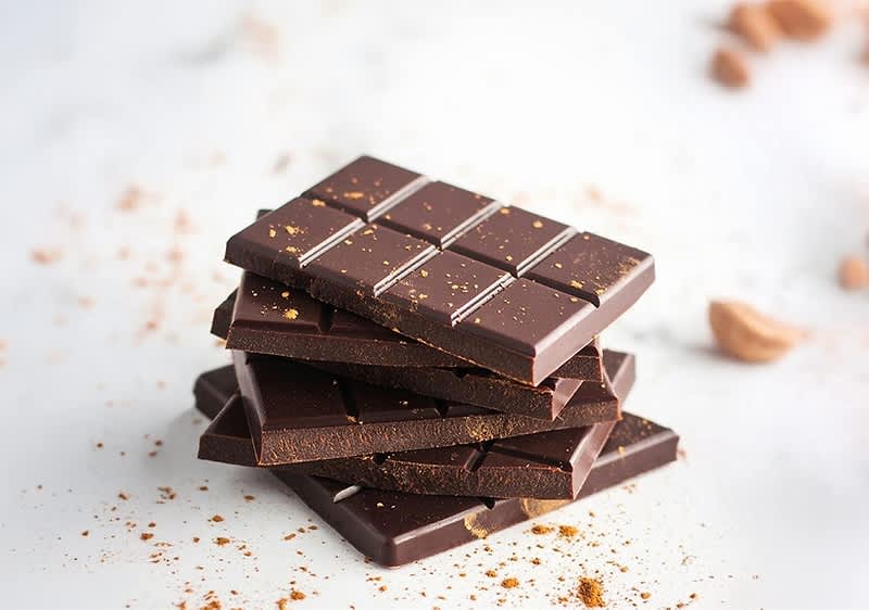 Schokoladentafeln gestapelt mit Kakaopulver auf weißem Hintergrund