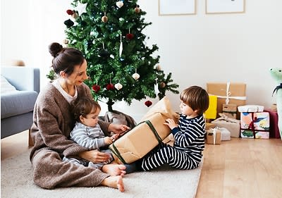 Mama mit zwei kleinen Kindern vor Christbaum