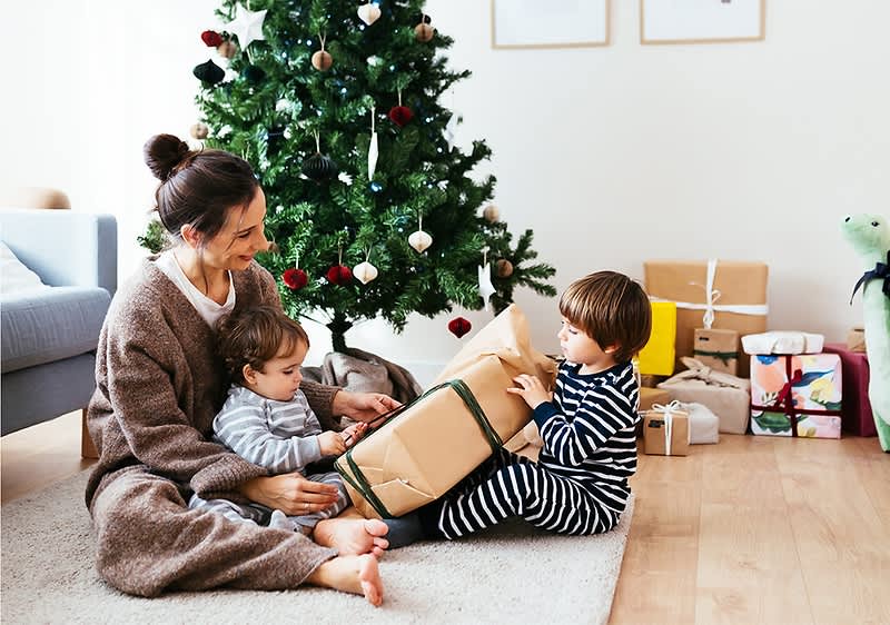 Mama mit zwei kleinen Kindern vor Christbaum