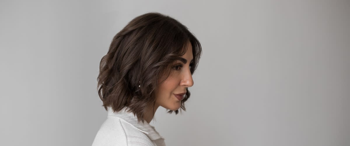 Kurzhaarfrisur mit braunen Locken und weißem Hemd