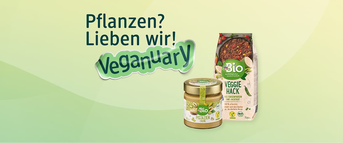 Grüner Werbehintergrund mit der blauen Überschrift „Pflanzen? Lieben wir!“ und dem grünen Schriftzug „Veganuary“, daneben zwei Produkte der Marke dmBio: links ein Glas „Pistazien Creme“ mit grünem Etikett, rechts eine Packung „Veggie Hack“ mit Bild eines Bratens und Schriftzug ‚VEGGIE HACK‘
