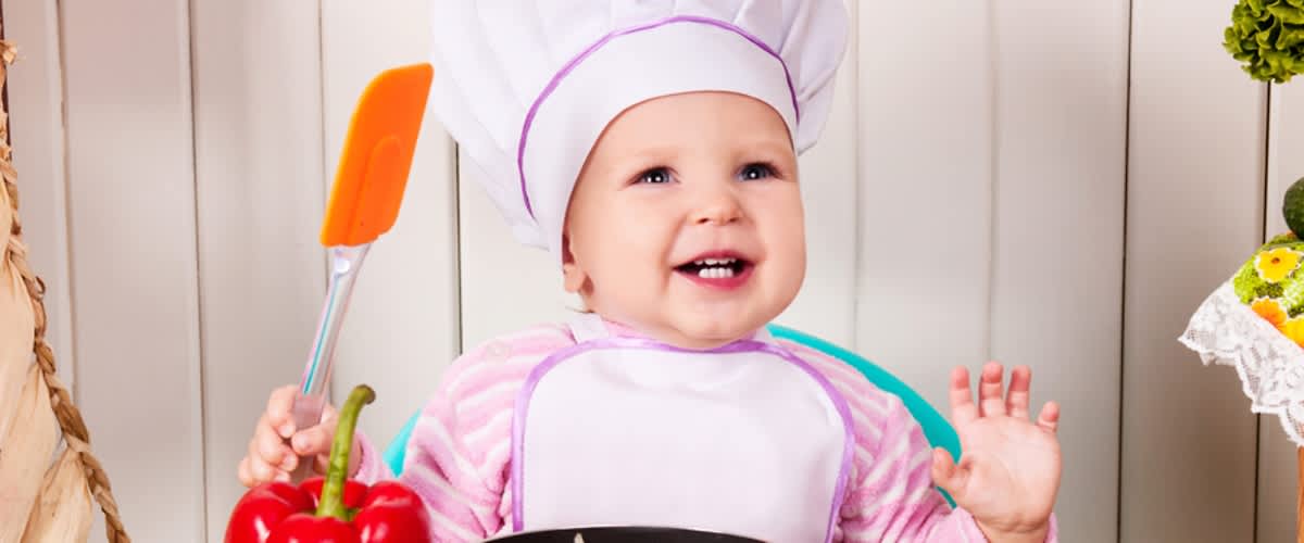 Kleinkind mit Kochmütze und Kochlöffel