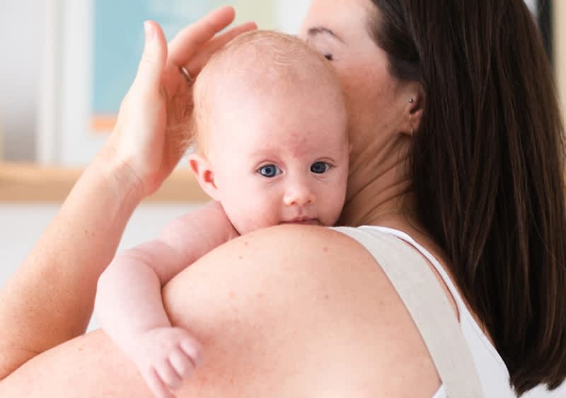 Baby schaut über die Schulter der Mutter