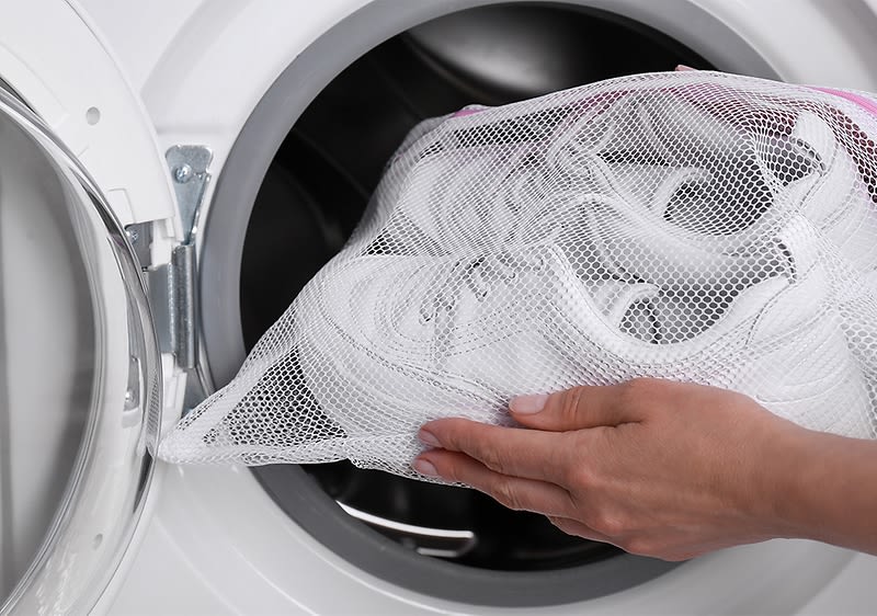 Frau die Schuhe in die Waschmaschine gibt