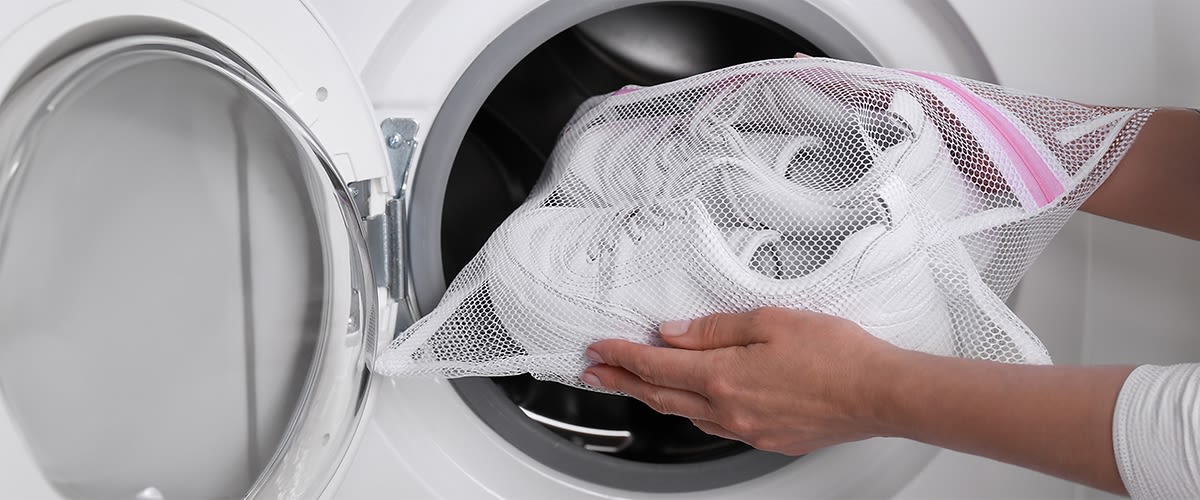 Frau die Schuhe in die Waschmaschine gibt