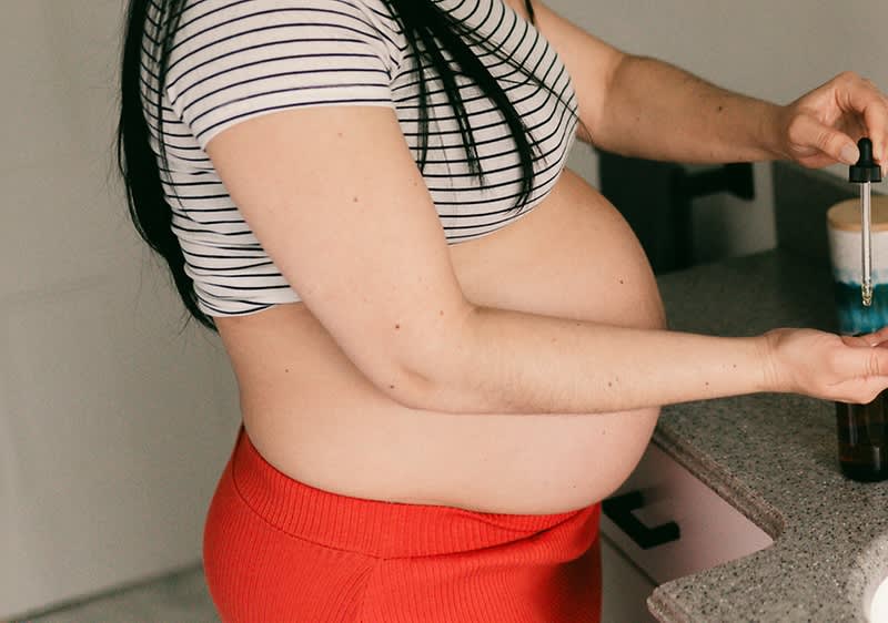 Frau verwendet Öl für Babybauch