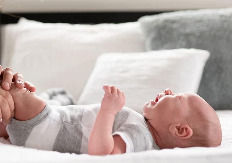 Weinendes Baby liegt auf einem Bett