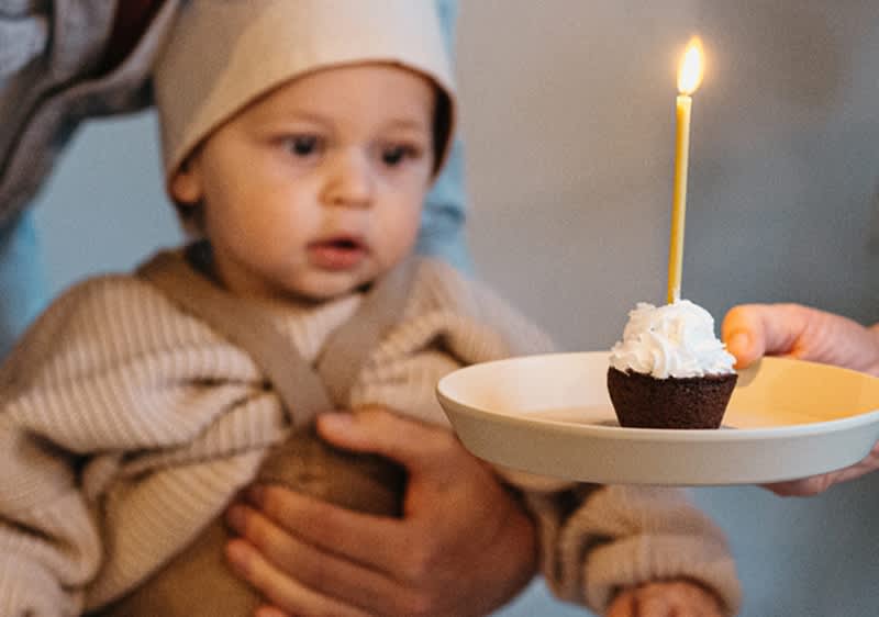 Baby bestaunt erste Geburtstagskerze auf Muffin
