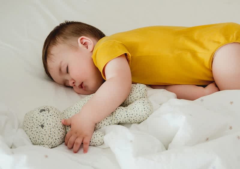 Baby schläft neben Teddybär