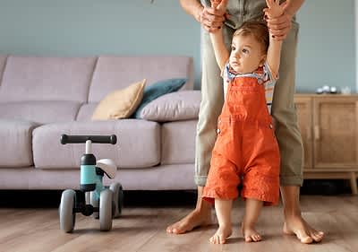 Baby steht aufrecht mit Papas Hilfe