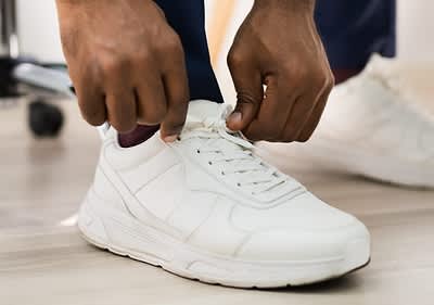 Mann bindet sich weisse Schuhe
