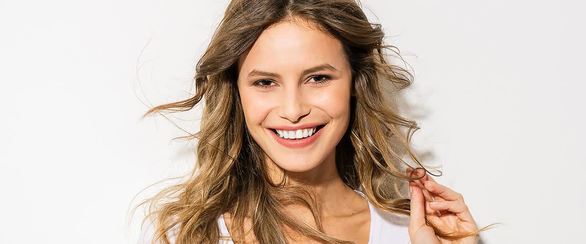 Frau mit weißem Laecheln und dunkelblonden langen Haaren
