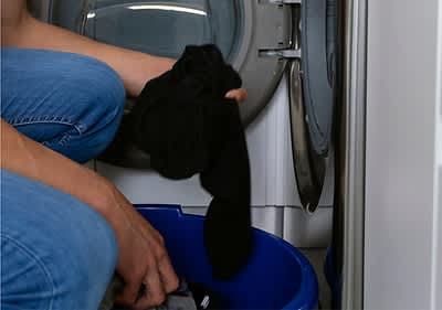 Person mit schwarzer Waesche vor der Waschmaschine