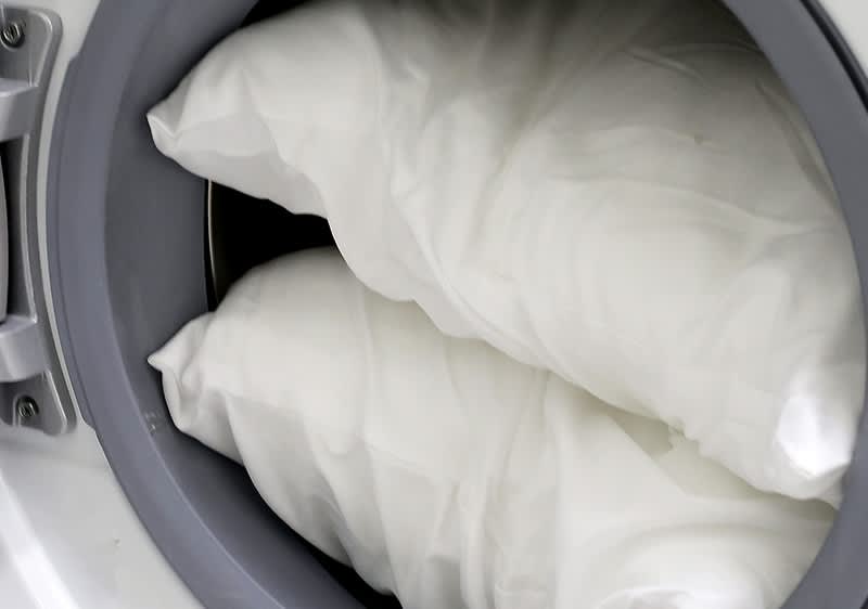 Kopfkissen in Waschmmaschine mit geoeffneter Tuer