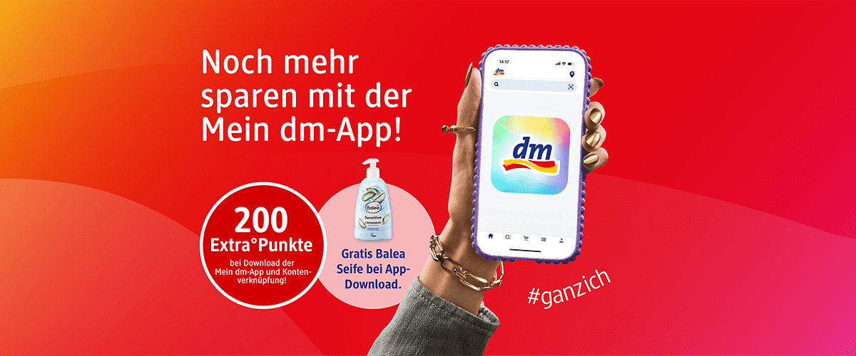 Rote Werbegrafik mit Text „Noch mehr sparen mit der Mein dm‑App!“, rechts eine Hand mit goldenen Nägeln, Smartphone mit dm‑App‑Logo auf dem Bildschirm, links zwei Kreise: weißer Kreis mit „200 Extra Punkte“ und darunter Hinweis zum Download, kleiner Kreis mit Bild einer Balea Flüssigseife und Text „Gratis Balea Seife bei App‑Download“, Hashtag „#ganzich“