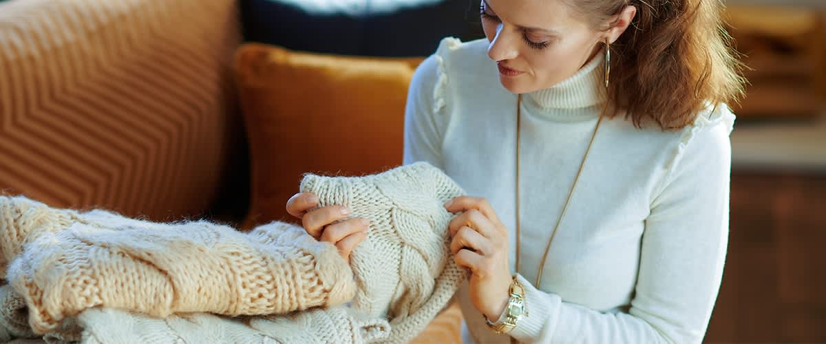 Frau mit Pulli in der Hand auf Couch