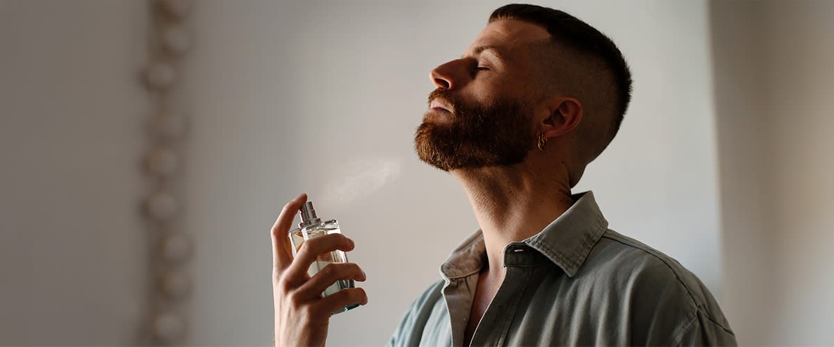 Mann bersprueht sich mit Parfum