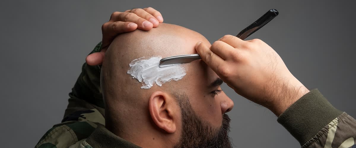 Mann mit Bart beim Glatzerasieren