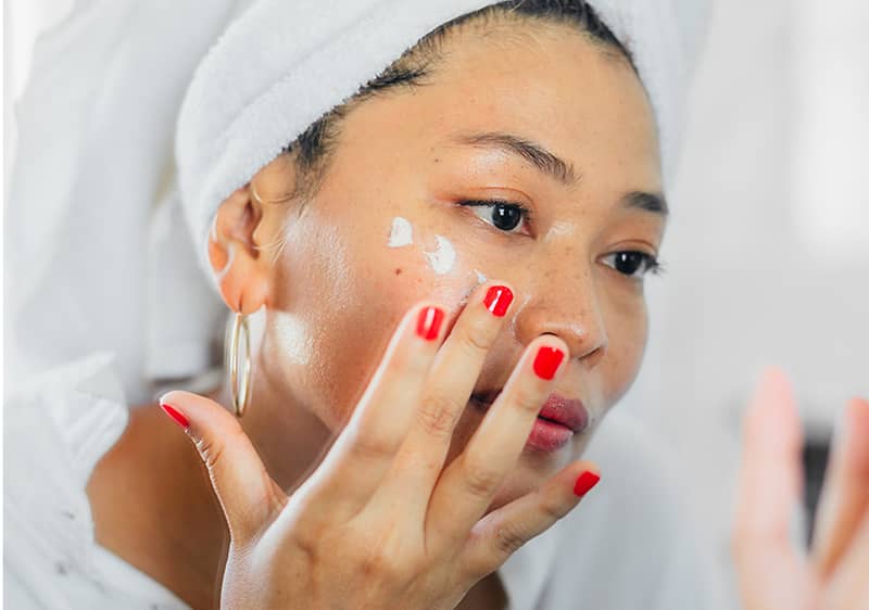 Frau beim Gesicht eincremen