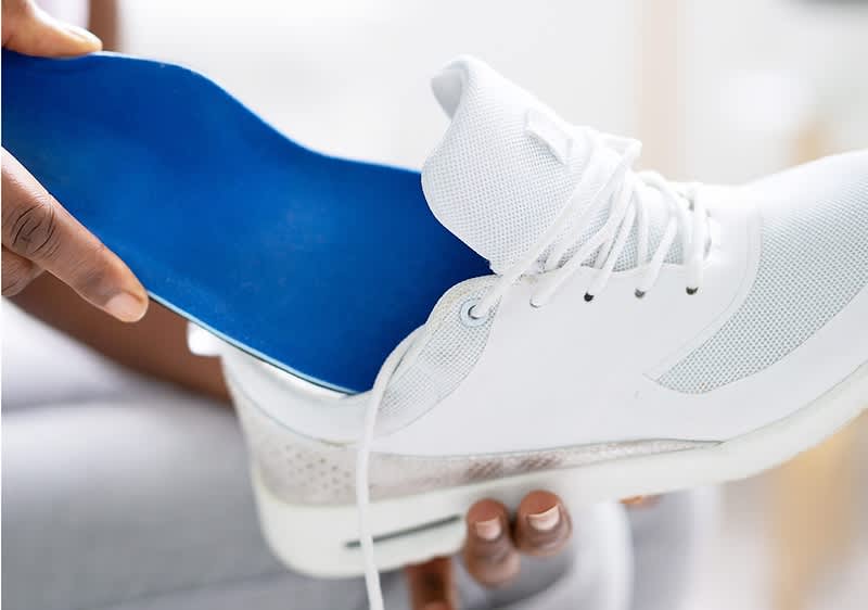 Blaue Schuheinlage wird in weissen Schuh eingelegt