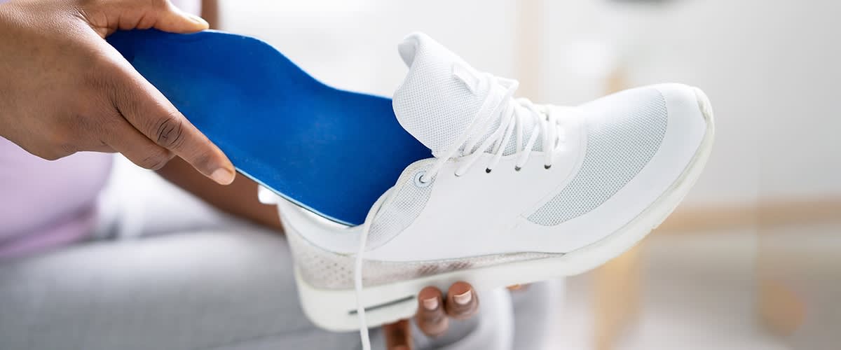 Blaue Schuheinlage wird in weissen Schuh eingelegt