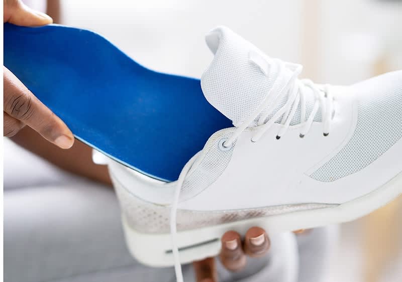 Blaue Schuheinlage wird in weissen Schuh eingelegt