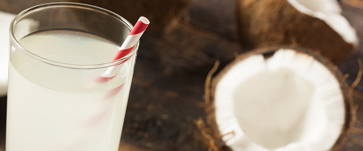 Glas mit Kokoswasser und rot-weißem Strohhalm