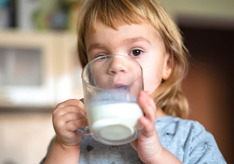 Kleines Kind trinkt aus Glas in Küche