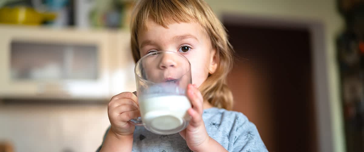 Kleines Kind trinkt aus Glas in Küche