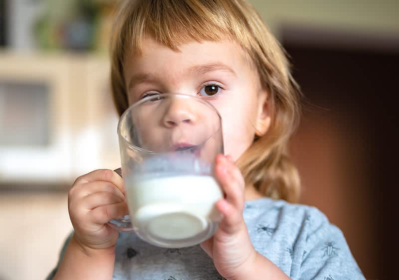 Kleines Kind trinkt aus Glas in Küche