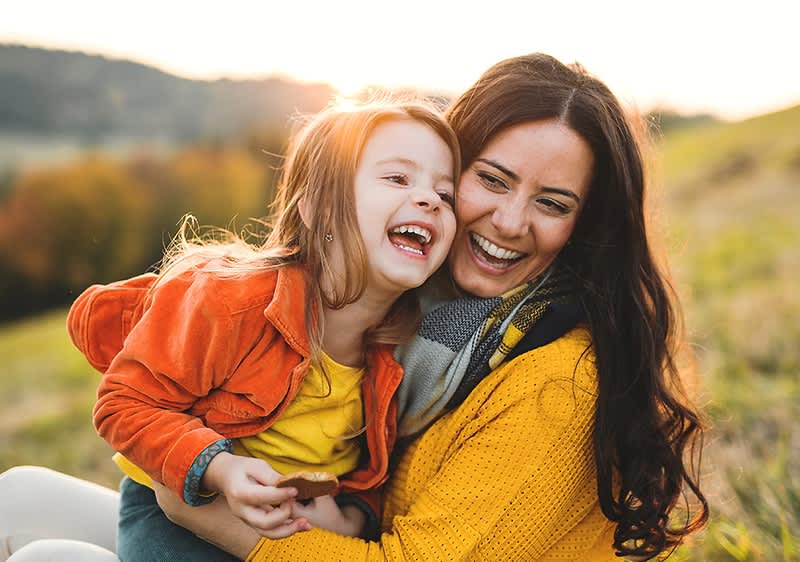 Mutter und Kind in Herbstlandschaft mit Bäumen und Wiese