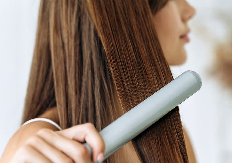 Haarglaettung mit Glaetteisen auf langem braunem Haar