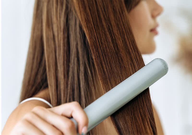 Haarglaettung mit Glaetteisen auf langem braunem Haar