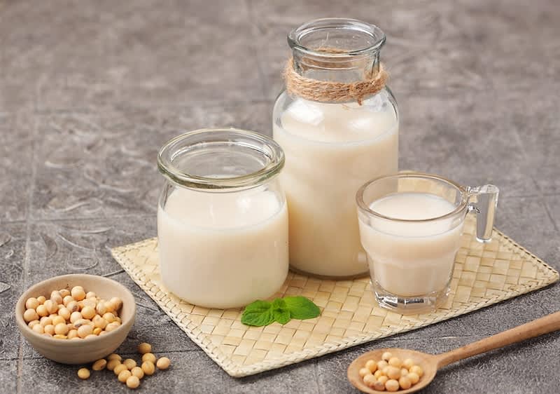 Sojamilch in Gläsern mit Sojabohnen auf einem Tisch