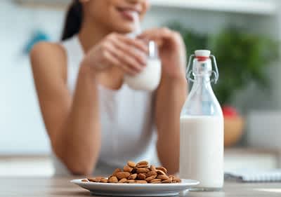 Mandelmilch mit Mandeln und Frau im Hintergrund