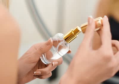 Parfümflasche in Frauenhand mit goldener Kappe