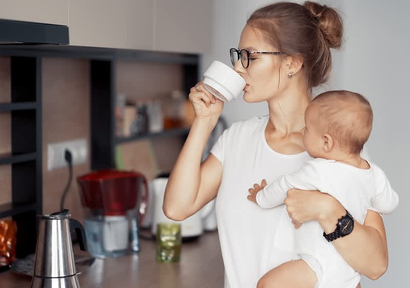 Mutter mit Baby in der Küche beim Teetrinken
