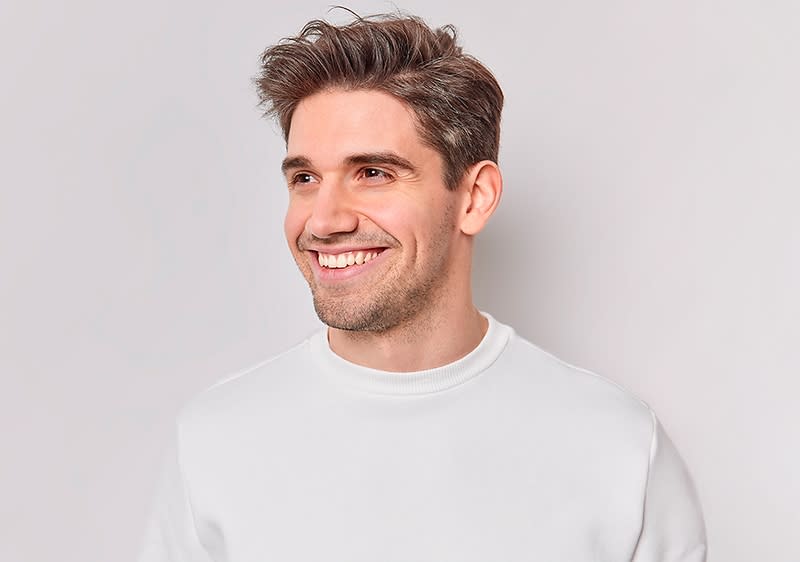 Mann mit weißem Pullover und braunen Haaren