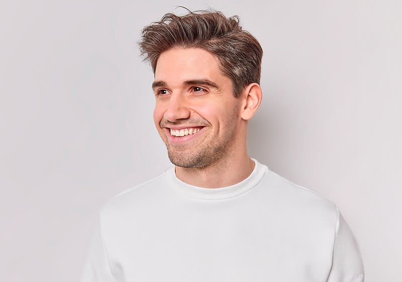 Mann mit weißem Pullover und braunen Haaren