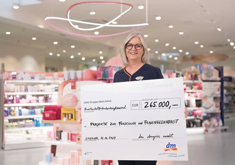 Spendenübergabe in Drogeriemarkt mit großem Scheck für Frauengesundheit