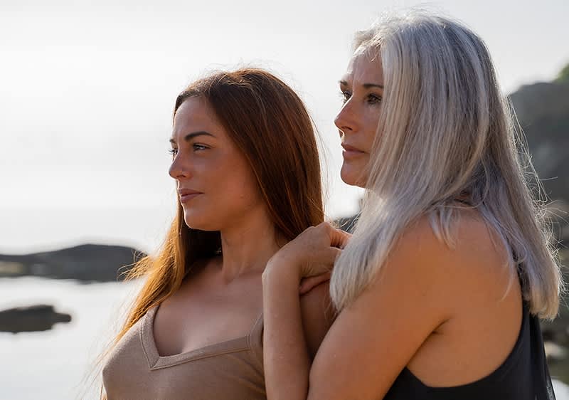 Zwei Frauen am Strand mit Felsen im Hintergrund