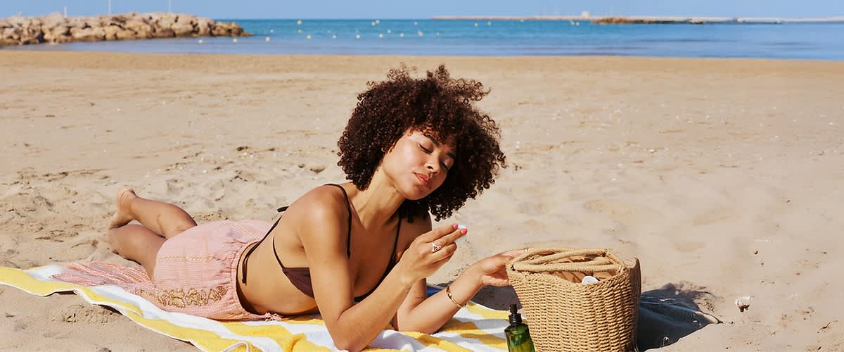 Frau am Strand mit Korb und Meer im Hintergrund