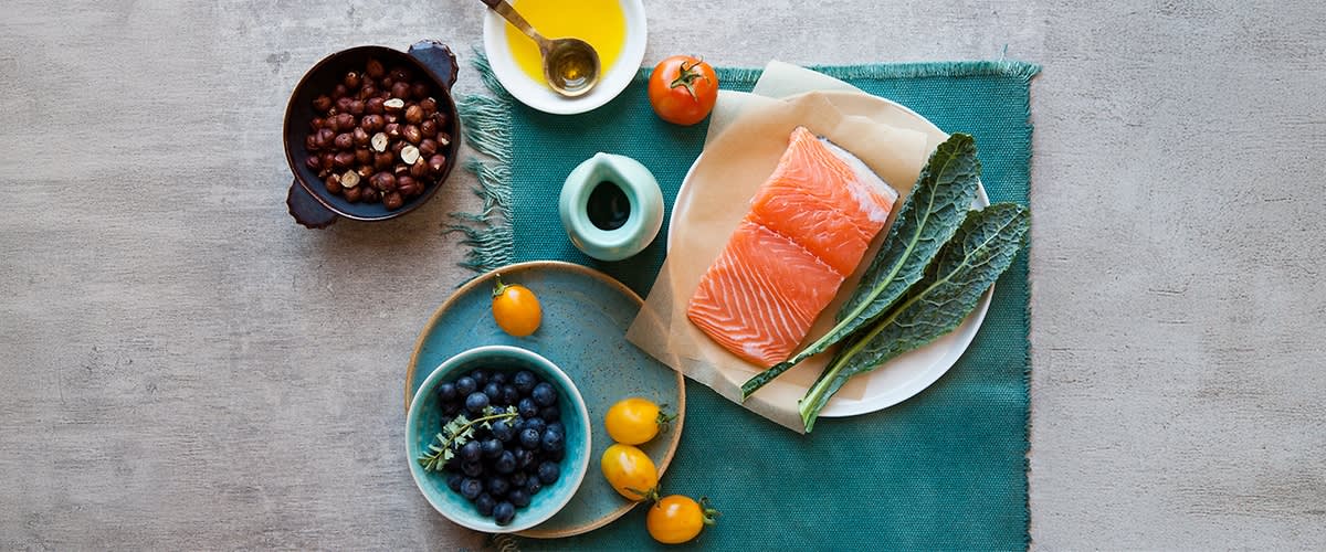 Gesunde Lebensmittel mit Lachs, Grünkohl, Blaubeeren, Tomaten und Nüssen auf einem Tisch