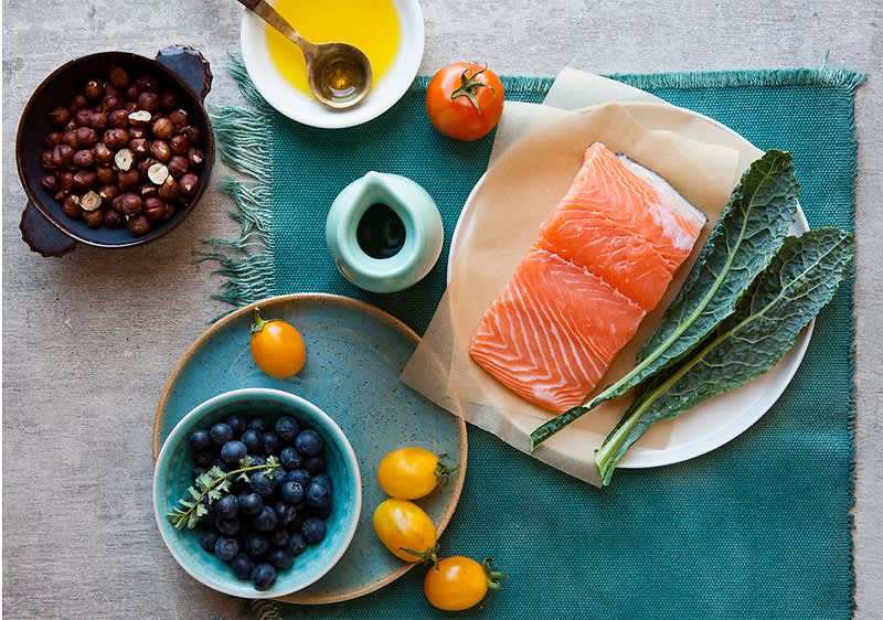 Gesunde Lebensmittel mit Lachs, Grünkohl, Blaubeeren, Tomaten und Nüssen auf einem Tisch